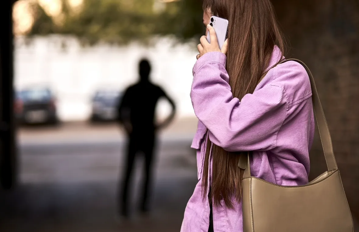 携帯電話を耳に当てるピンクの服の女性